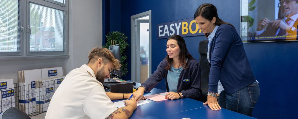 un ufficio di EasyBox in cui il personale sta parlando cordialmente con alcuni clienti. Tutti hanno un’espressione rilassata.